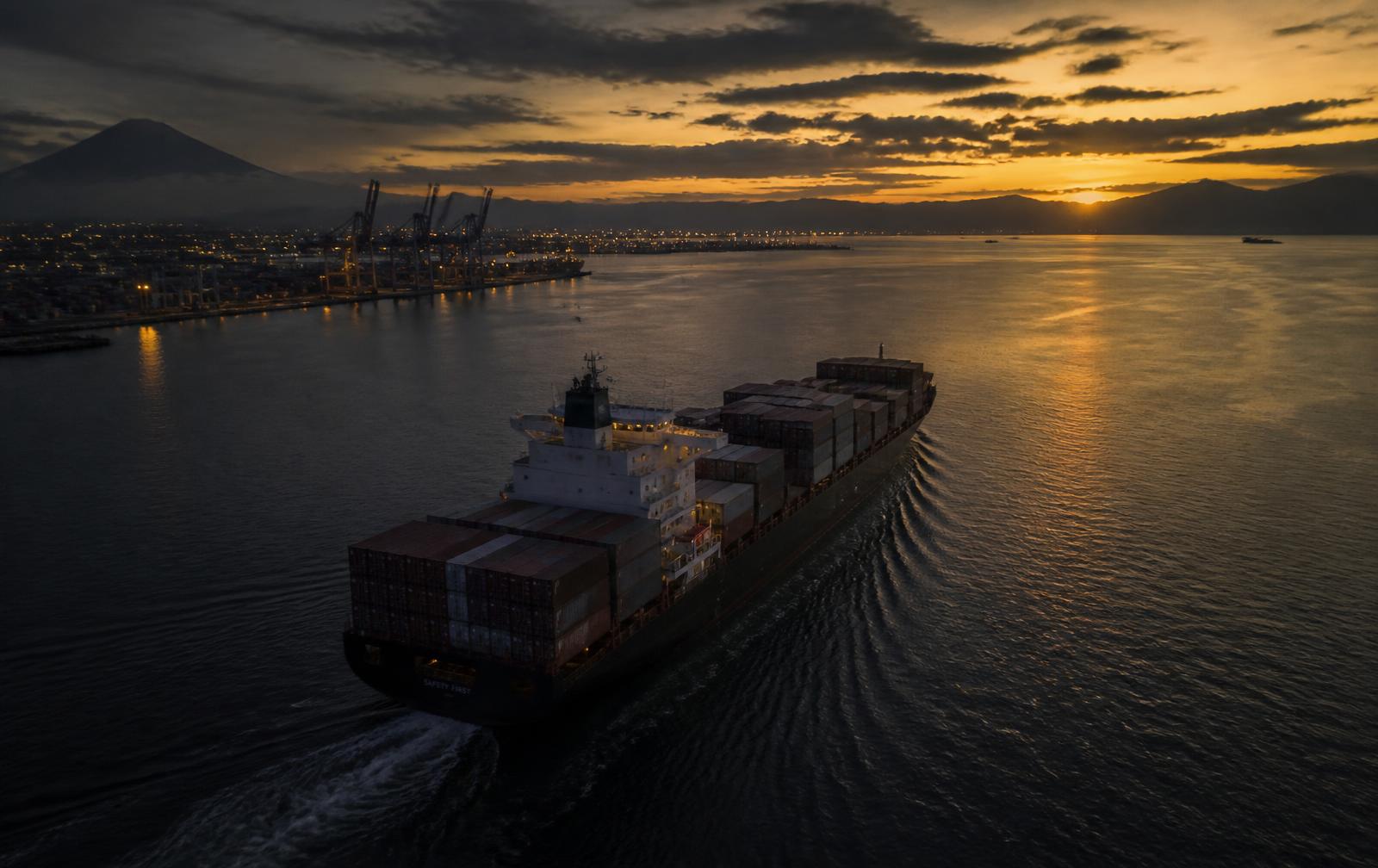 Container ship departing an Indonesian port at dusk